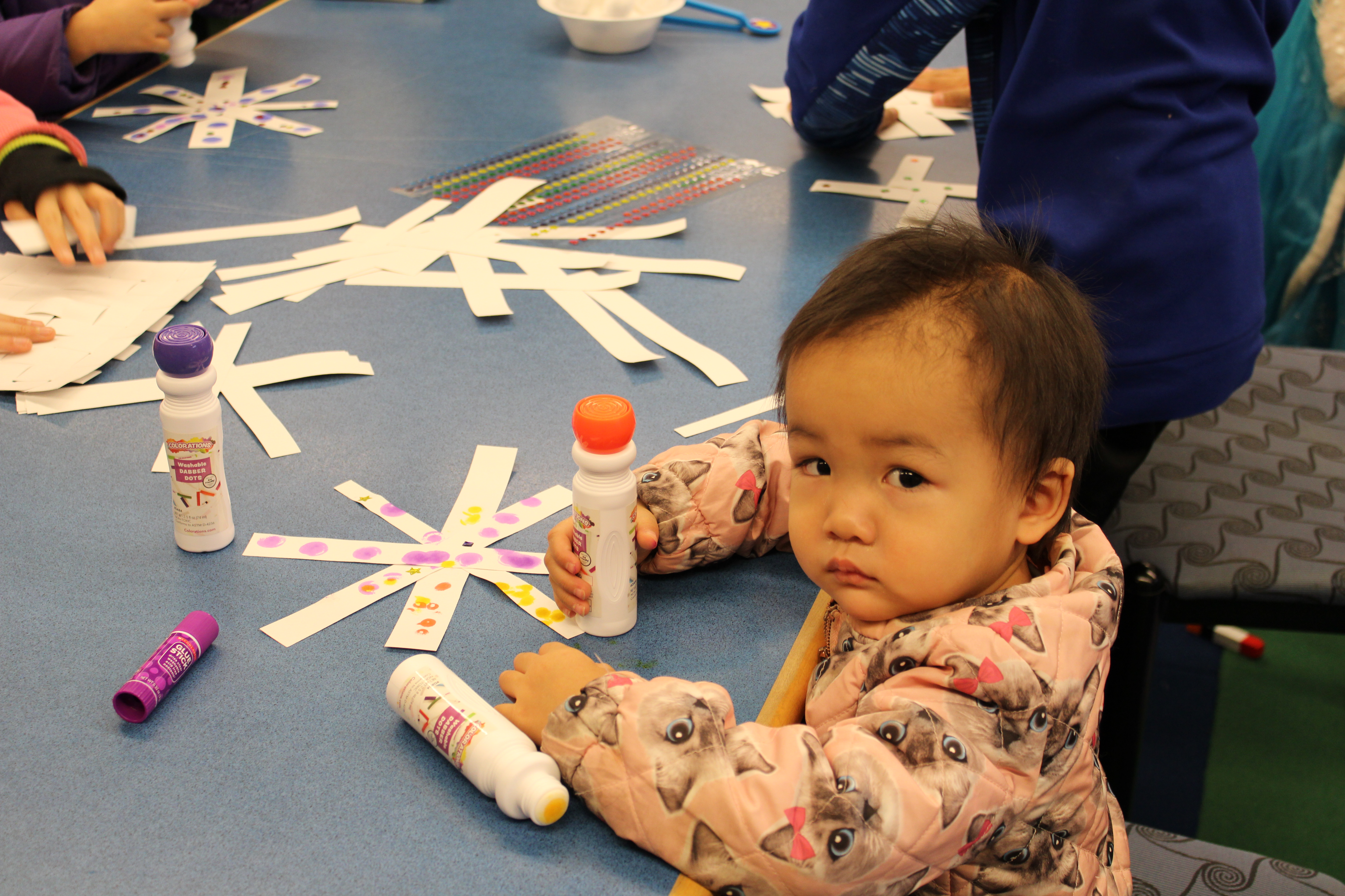 Young child decorating a paper snowflake