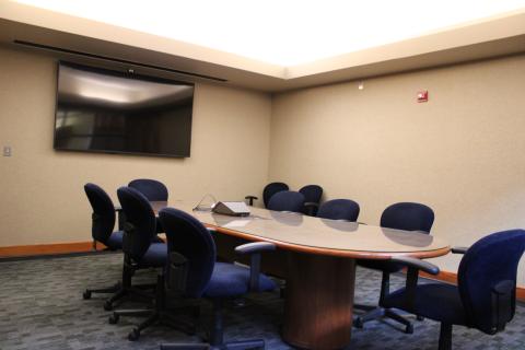 rolling chairs around a long conference table with a screen on the far wall