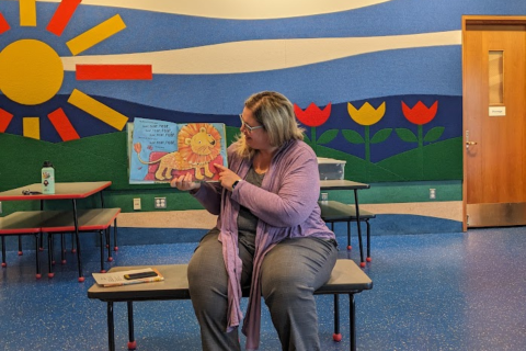 Ms. Emily reading a picture book in the brightly colored Main Library Youth Activity Center