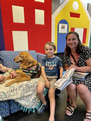 Parent and child reading to a dog.