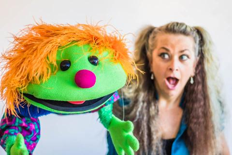 Woman making a silly face at a brightly colored puppet