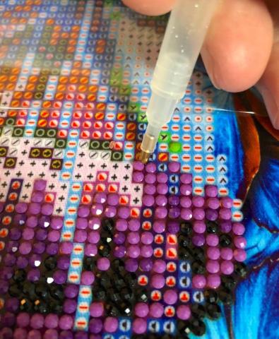 tiny diamonds being adhered to an image by a hand
