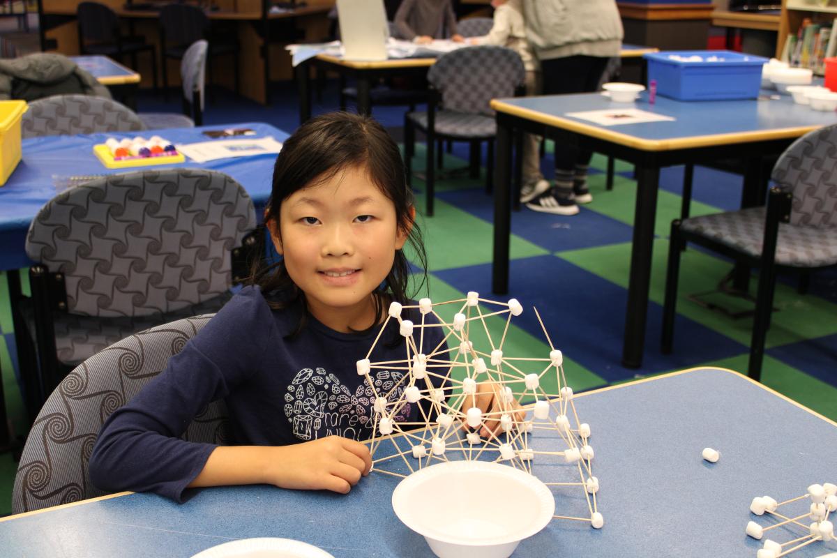 Child building with marshmallows and toothpicks.