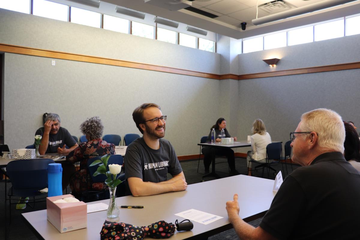 Man smiling at a person seated across from him in the Main Library Meeting Room